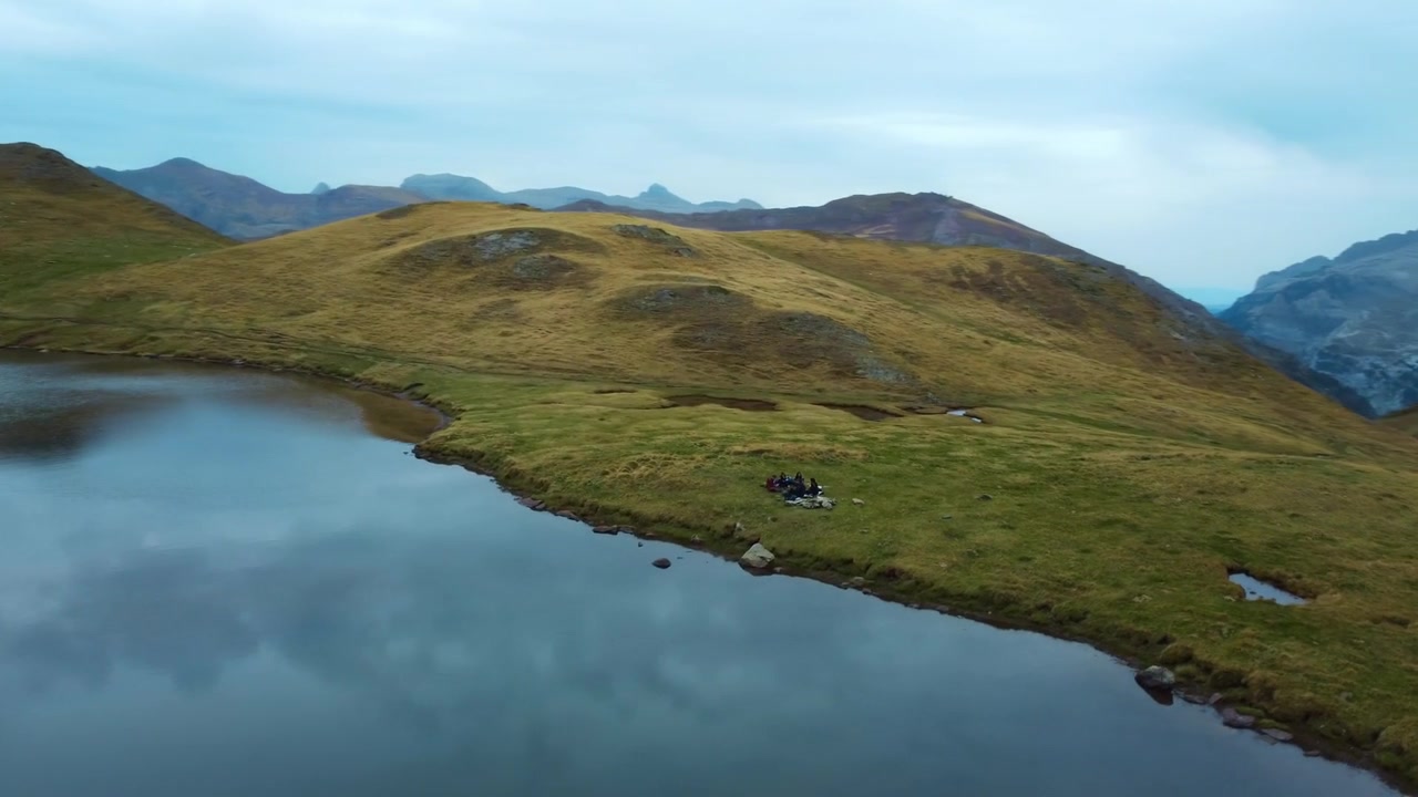 Vista aerea con drone di un remoto lago delle Highlands in Scozia. Montagne, colline erbose e acqua calma circondano il paesaggio isolato sotto un cielo coperto