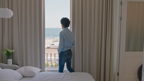 junger mann trinkt kaffee im hotelzimmer und schaut aus dem fenster, plant voraus und genießt den blick auf das meer