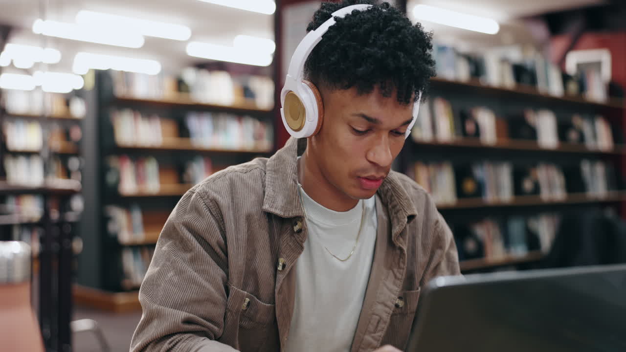 hombre estudiando en la biblioteca con auriculares