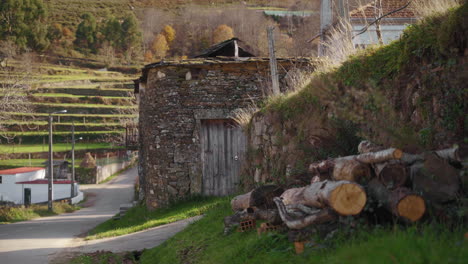 logs of wood next to a stone house in a portuguese countryside village