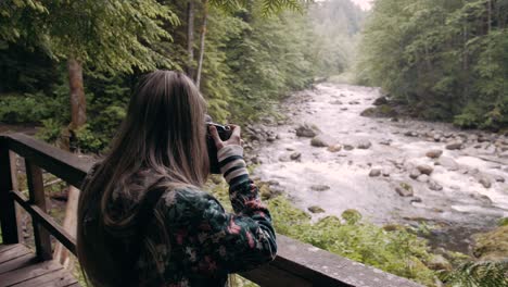 slow motion shot of a female photographer taking photos of a river in vancouver lynn valley, canada