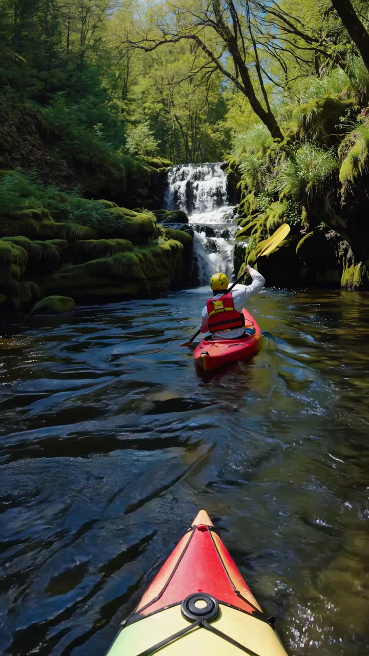 Video in stile POV di canoisti che remano verso una cascata in una foresta lussureggiante, ripreso da una prospettiva bassa