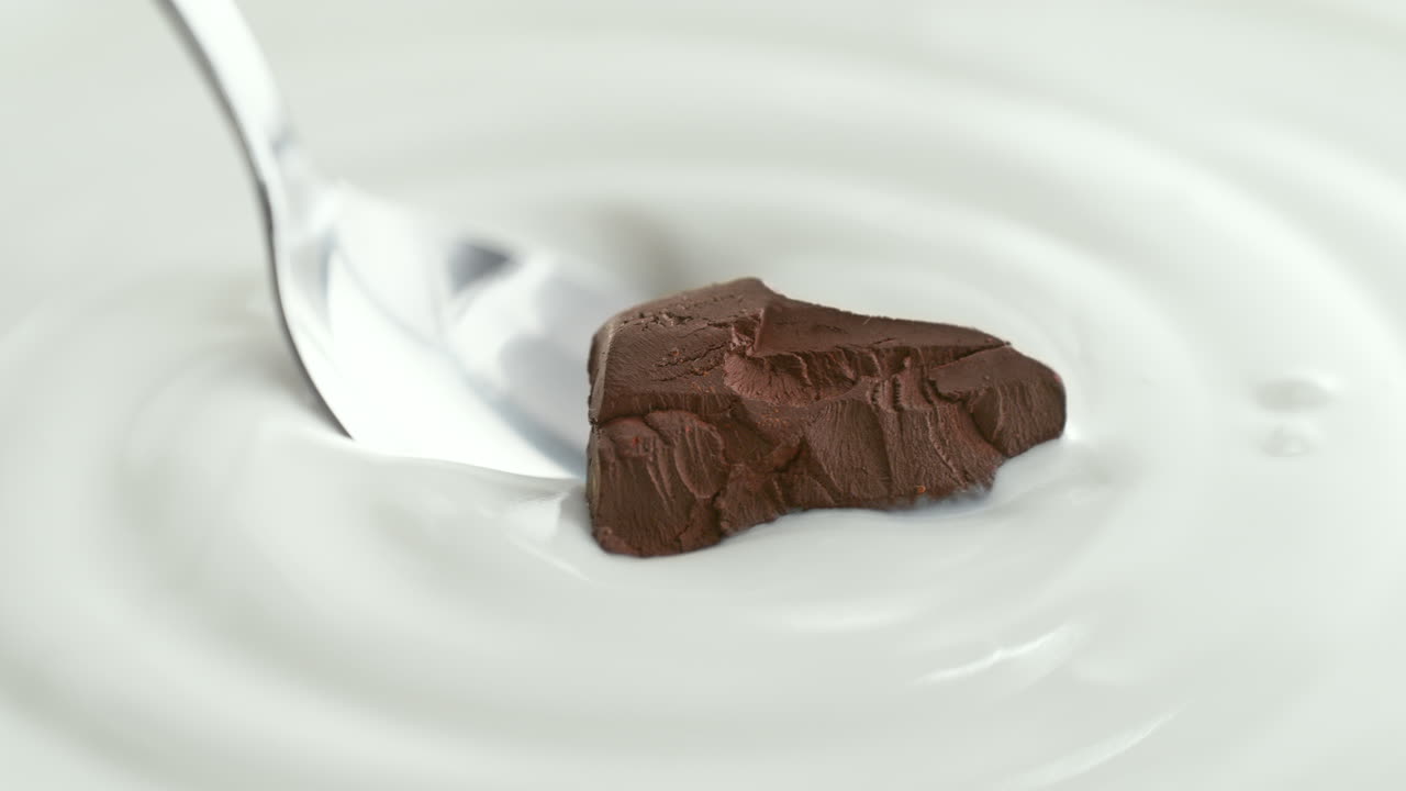 Chocolate Chunk Scooped with Silver Spoon from Creamy Thick Yogurt in Macro and Slow Motion