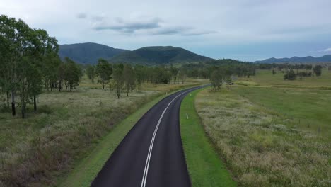 drone shot flying above country road, drone following road bend
