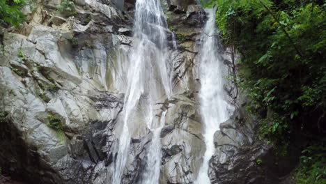 magical aerial shot of waterfall in northern thailand, slow rise up