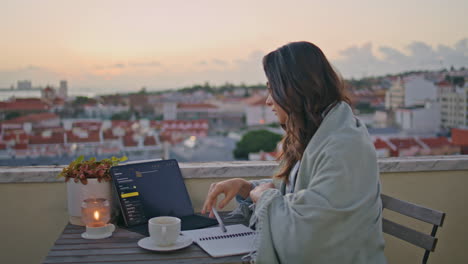 contemplative freelancer working laptop at sunset cityscape terrace closeup