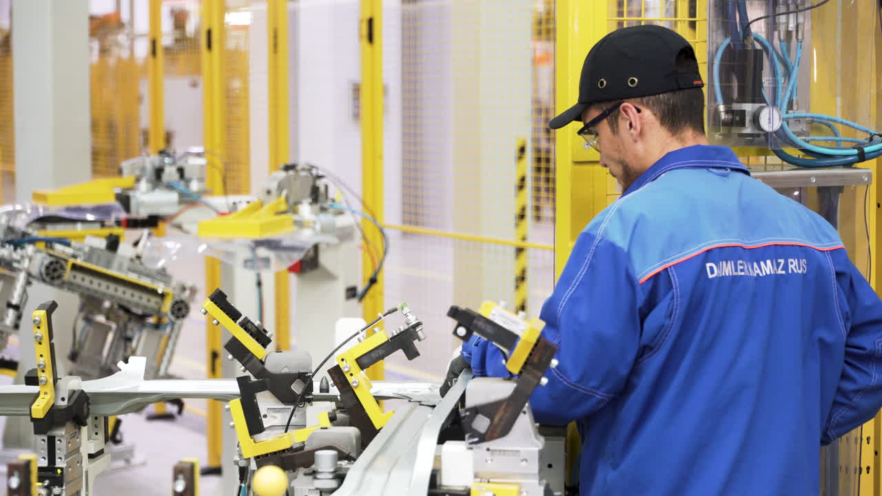 Factory worker inspecting and working on a car part production line