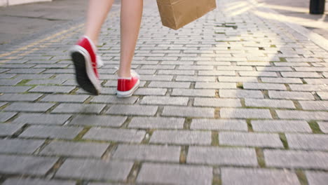 woman walking down cobblestone street with shopping bag