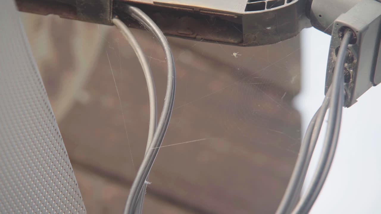 Spider on it&rsquo;s web indoors with the web attached to cables of something