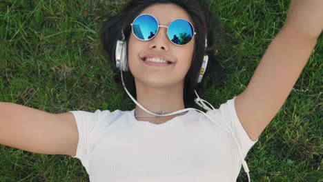 woman relaxing in grass with headphones and sunglasses