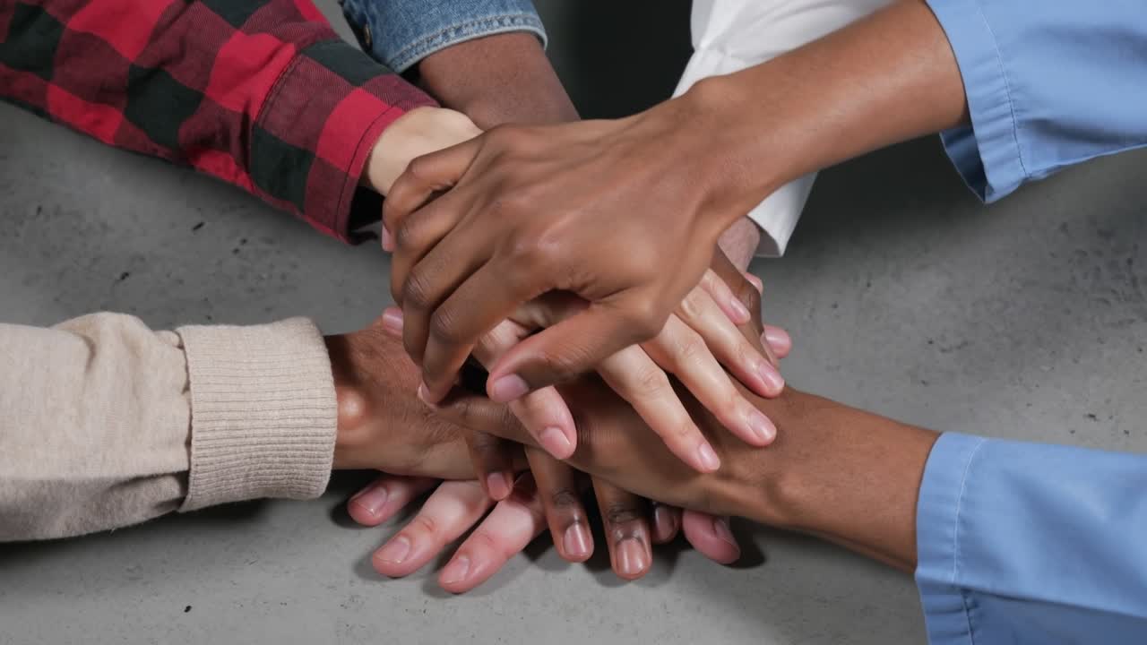 Diverse group of people stacking hands in center for unity teamwork and cooperation concept