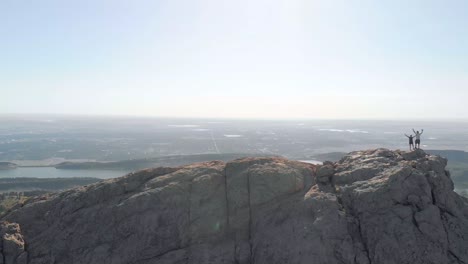 Drone-shot-of-mountainous-terrain,-hikers-and-cityscape-in-the-distance