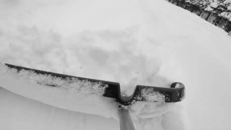 using large shovel to remove fresh snow from walkway