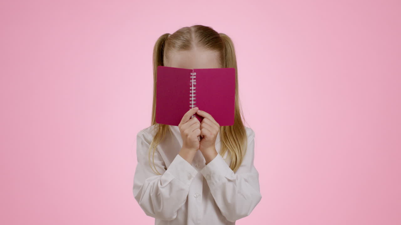 Child Hiding Behind a Notebook