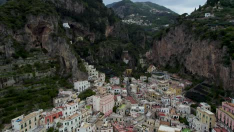 fly over dramatic townscape of amalfi behind sheer rocky mountains in campania, italy