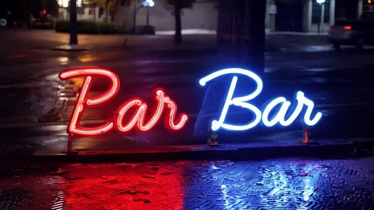 Neon sign reading bar bar flashes red and blue on a city street at night, its colors reflected in the wet pavement