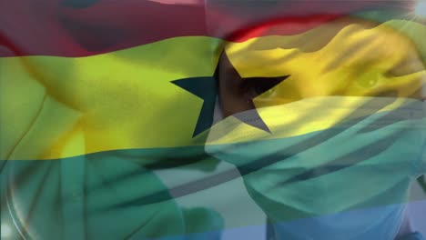 animation of waving ghana flag against caucasian female surgeon wearing surgical mask at hospital