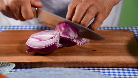 cutting red onion on wooden board  woman hand cutting red onion on the table