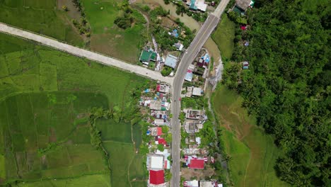 aerial top-down flyover of idyllic village town with a fork road and surrounding lush greenery. bato, catanduanes, philippines