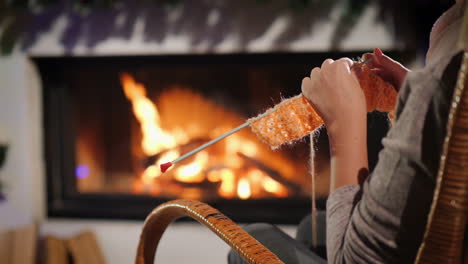 descansar en una noche de invierno - una mujer teje sentada junto a una chimenea decorada para navidad