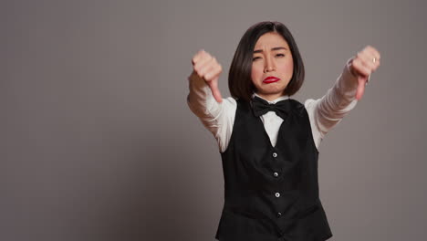 Receptionist-showing-thumbs-down-sign-over-grey-background