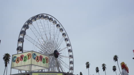 empty ferris wheel spins, candy concessions counter and palm trees, slow motion low angle