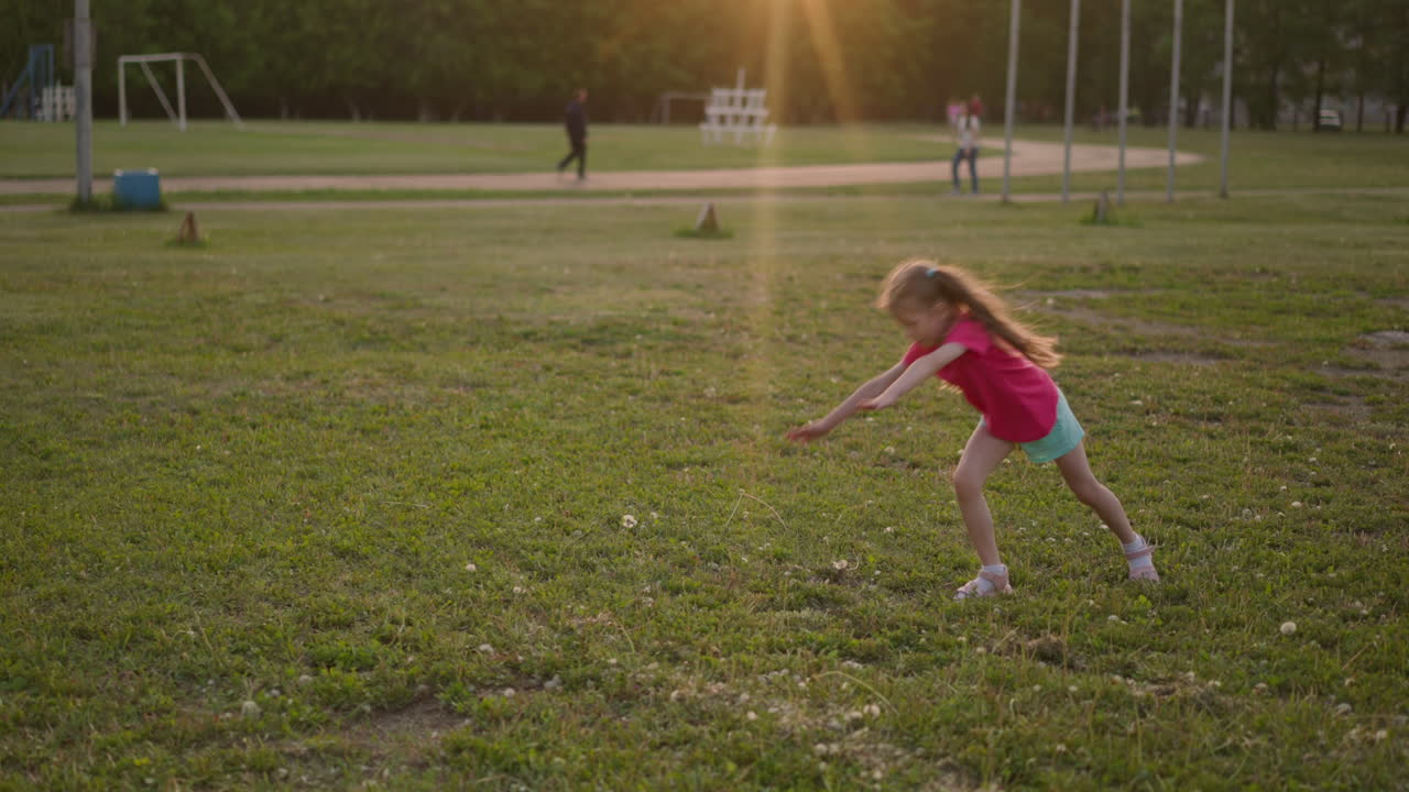 niña deportiva con cola de caballo hace rueda de carro en la hierba