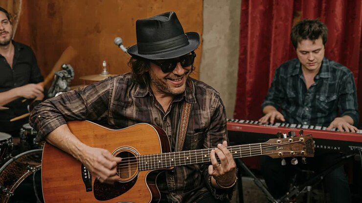 Un chitarrista inizia una canzone strimpellando la chitarra, mentre la band tiene il ritmo con batteria e tastiere, durante le prove.