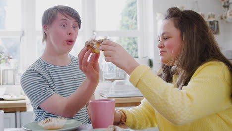 young downs syndrome couple enjoying tea and cake in kitchen at home