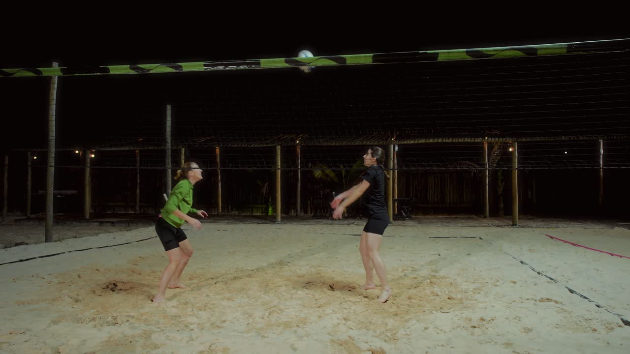 Women playing beach volleyball at night