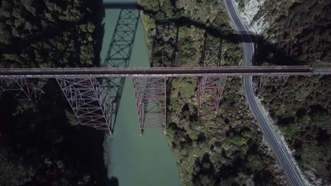 vista aérea, volando sobre un puente abandonado en un día soleado en nueva zelanda, tiro revelador