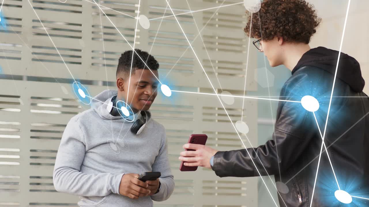 Hoodie man taking maroon phone from peer comparing screens while network overlay sharing tech data
