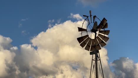 old broken windmill against white clouds and blue sky- handheld