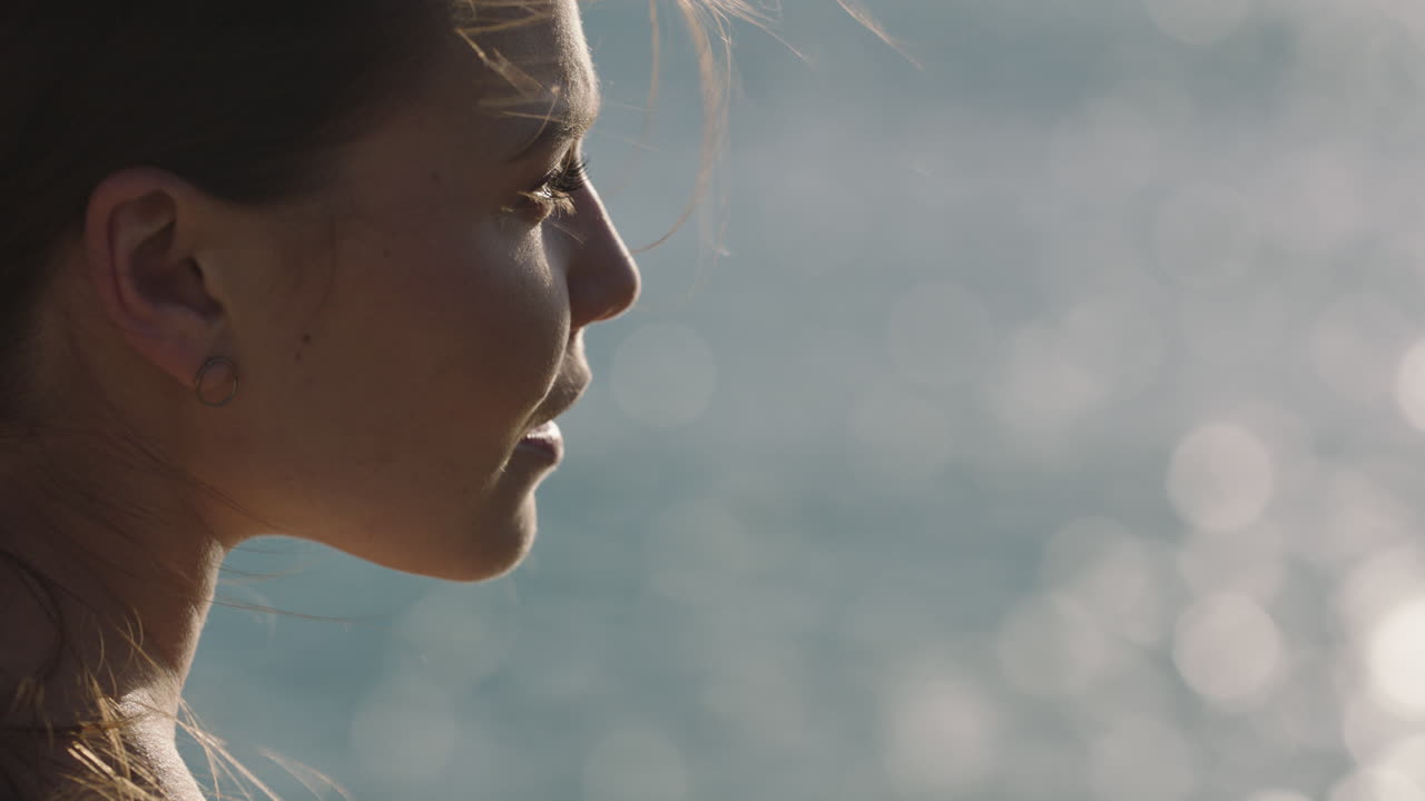 primer plano de una joven mujer caucásica disfrutando de un tranquilo día de verano en la orilla del océano relajando el viento soplando el cabello mirando pensativa contemplativa