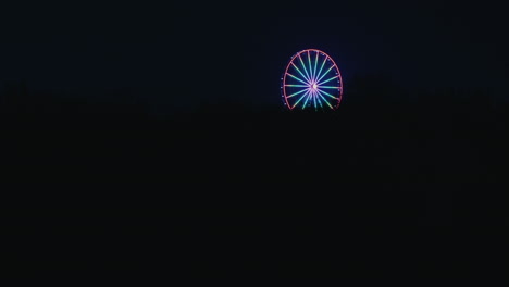 ferris wheel illuminated with colorful light appearance at pitch black night, tallinn, estonia t1 mall