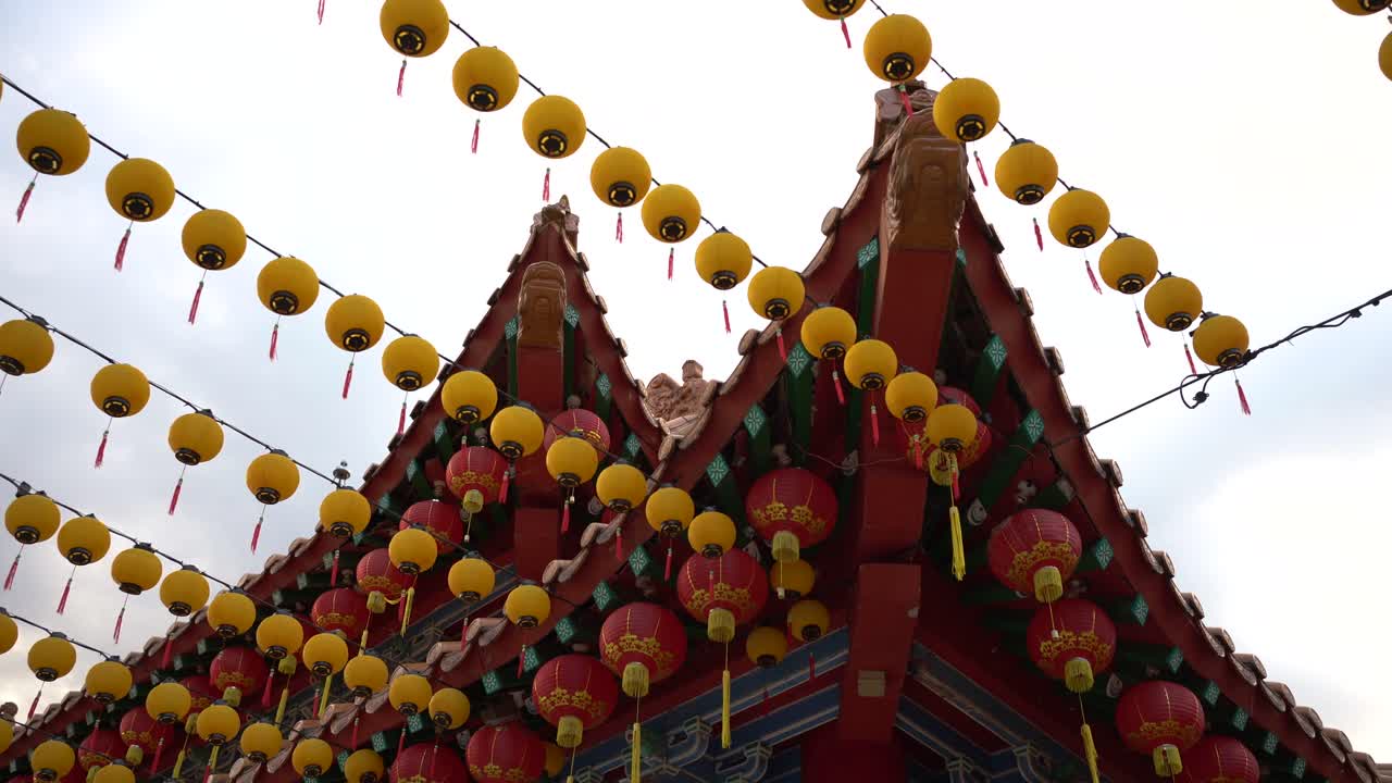 Decorative red and yellow lanterns sways in the breeze in a Chinese Temple.