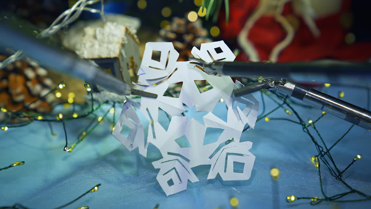 Robotic tool cutting paper snowflake. Smart robot making Christmas decorations. Modern intelligent equipment preparing for New Year.