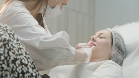 woman undergoing facial treatment at cosmetologist clinic