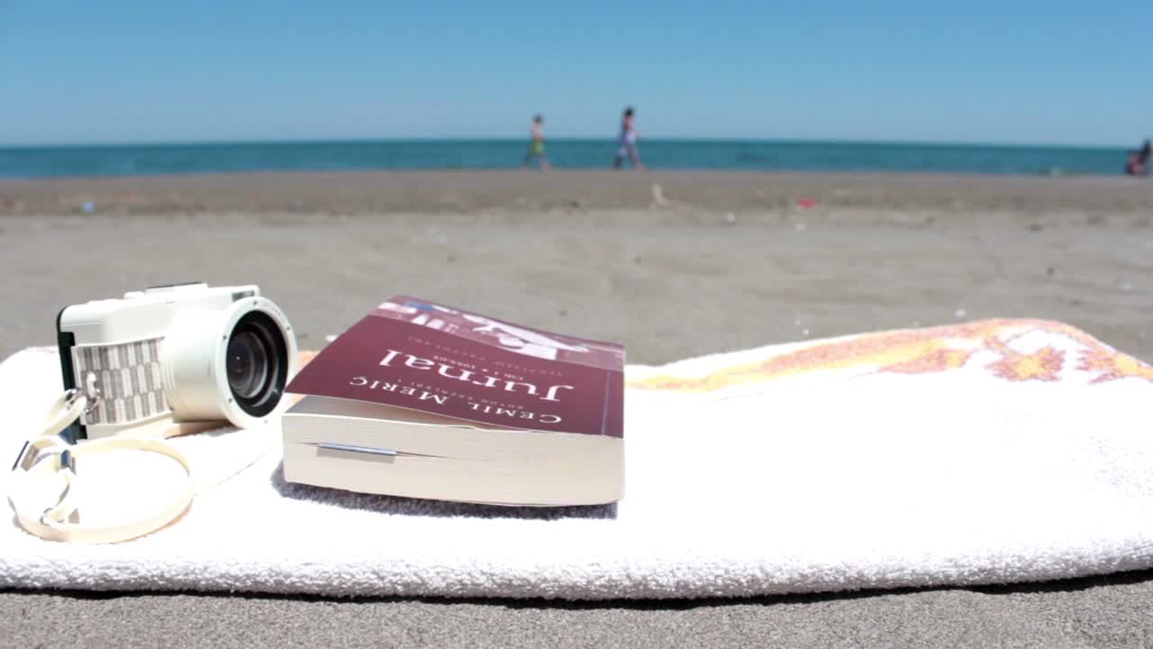 libro abierto en una toalla acostado en una playa soleada