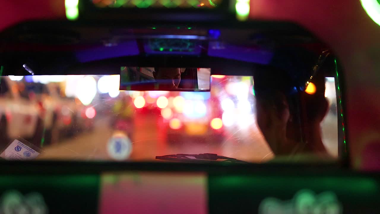 Colorful tuk-tuk ride through lively Phuket streets at night, showcasing vibrant lights and dynamic urban atmosphere
