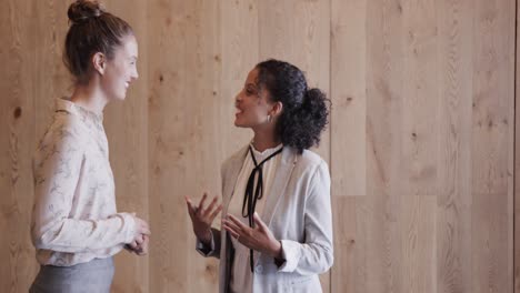 happy diverse female colleagues in discussion in office foyer, slow motion