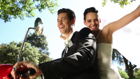 Happy-newlyweds-riding-a-red-scooter-in-the-park