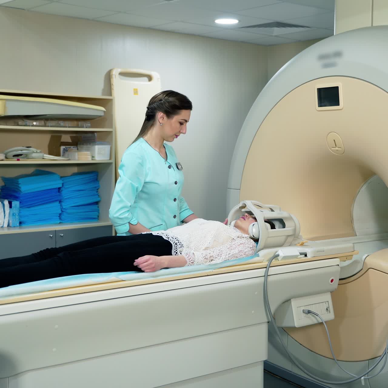 Medical scanning equipment and a female patient. Doctor preparing patient before the mri procedure. Woman lays in magnetic resonance image device.