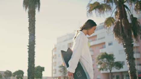 cool lady holding skateboard walking at city. woman having fun relaxing on alley