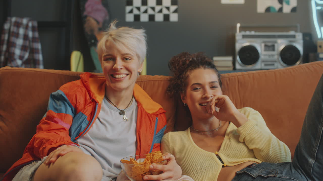 Meninas Alegres Assistindo TV, Conversando e Rindo no Sofá na Sala de Estar
