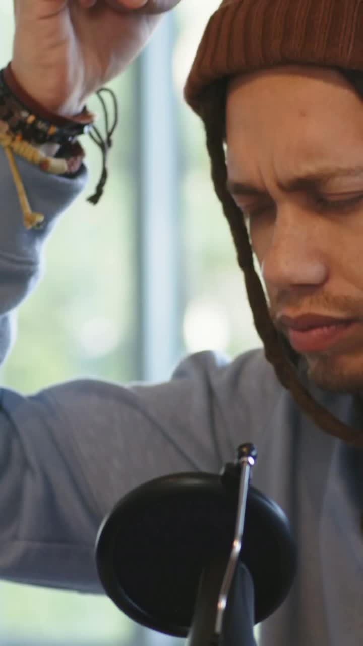 Vertical video: Hearing playback cue, man with beanie adjusting ear and recording into mic at home