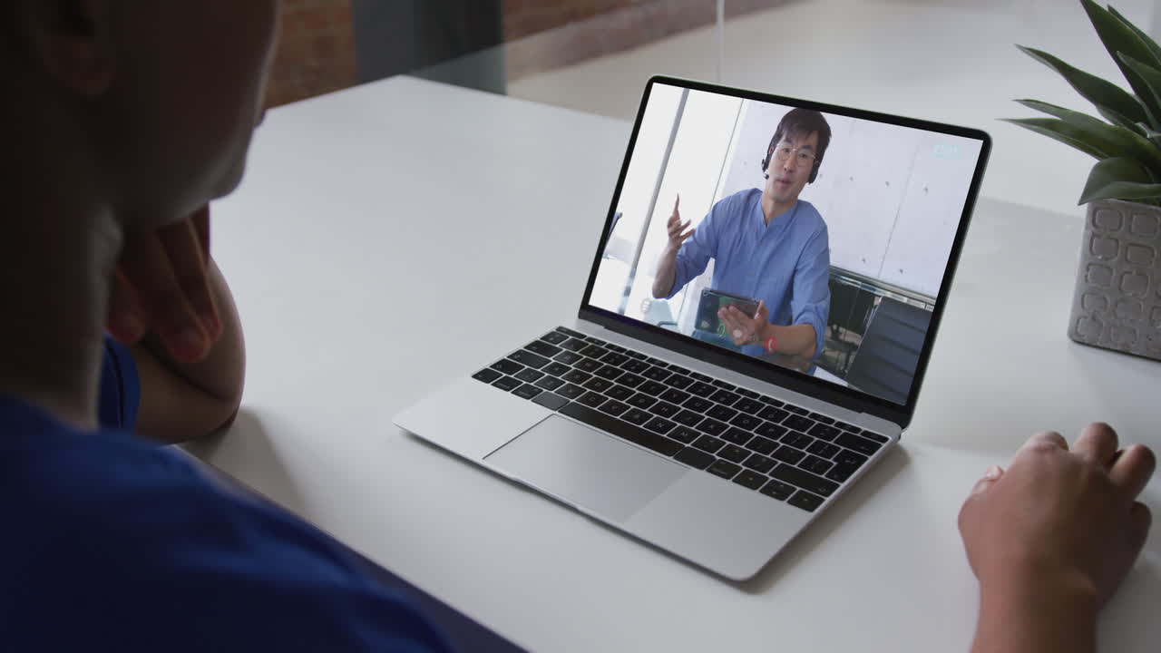 Mid section of african american woman having a video call with male colleague on laptop at office