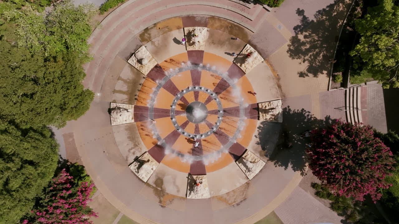 Top-down view of Chattanooga’s fountain plaza with outward spraying water jets, surrounded by park greenery in Coolidge Park