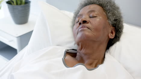 african american senior female patient sleeping in bed in hospital room, slow motion