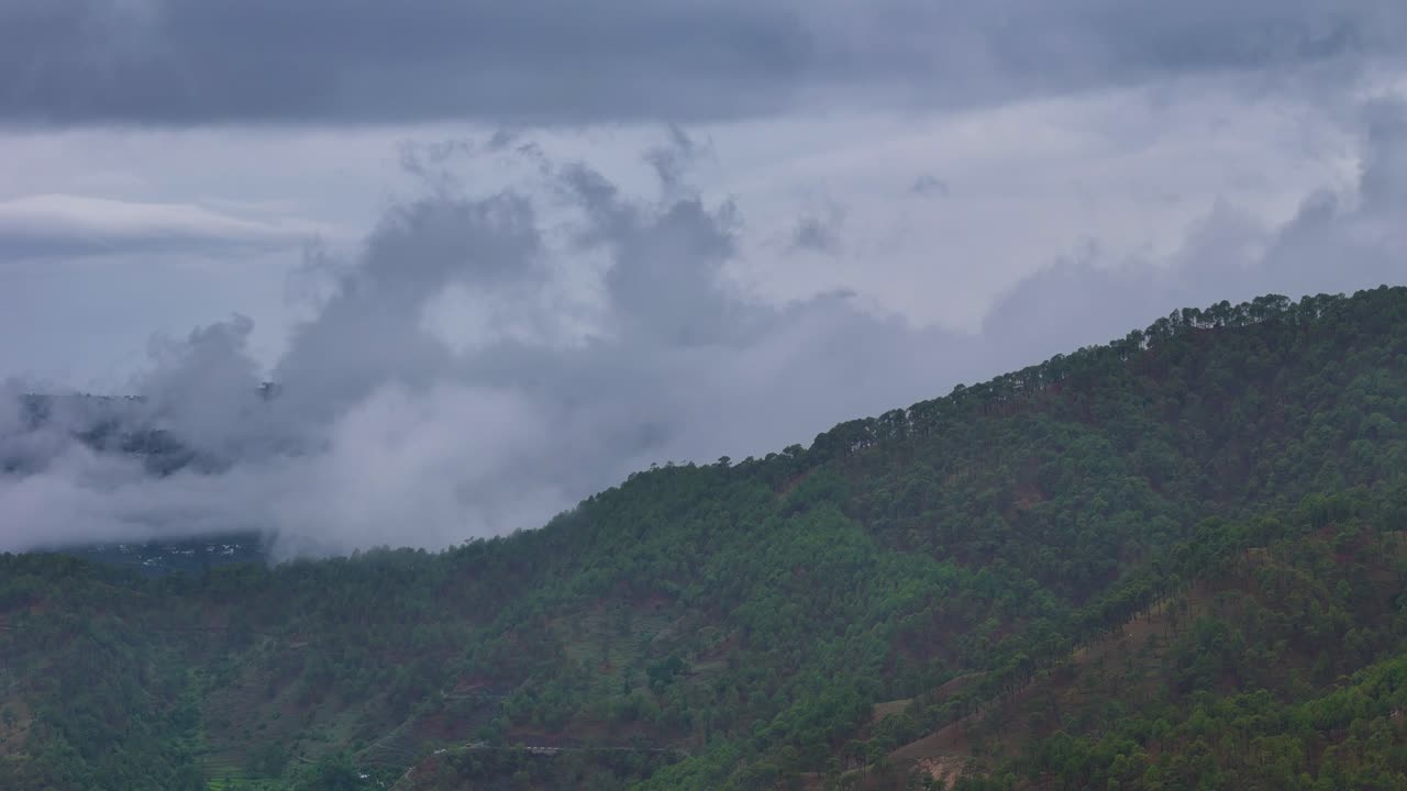 Aerial drone shot capturing the dreamy atmosphere of a cloud-draped mountain landscape at dawn.